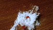 Pill capsules falling on white substance on wooden table