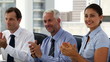 Business people clapping sitting in board room