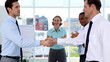 Businessmen shake hands while other business people applauding