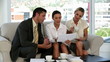 Three business people on a sofa looking at a document