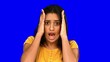 Shocked woman putting hands on head on blue screen