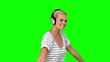 Young woman listening to music on green screen