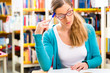 Photo: Student with pile of books learning in library Student with pile of books learning in library