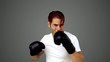 Sportsman boxing in front of the camera on grey background