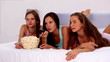 Video: Friends eating popcorn and watching tv on bed in their pajamas Friends eating popcorn and watching tv on bed in their pajamas
