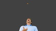 Man catching an orange segment with mouth on grey screen
