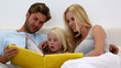 Parents and daughter reading book together