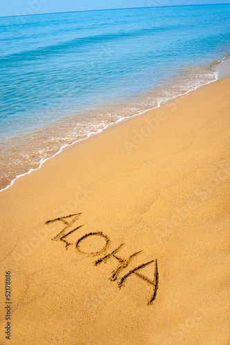Photo: Word Aloha written in sandy on tropical beach Word Aloha written in sandy on tropical beach