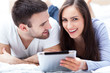 Photo: Couple with digital tablet lying on bed Couple with digital tablet lying on bed