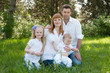 Happy beautiful family sitting on a green grass