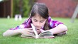 Little girl reading a book in summer on grass.Girl  Reading