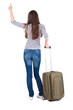 Back view of brunette woman with suitcase thumbs up