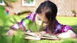 Little girl reading a book in summer on grass.