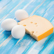 Fresh cheese and raw chicken eggs on wooden boards