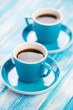 Vertical shot of two turquoise espresso cups on wooden boards