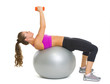 Fitness woman making exercise with dumbbells on fitness ball