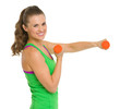 Smiling healthy young woman making exercise with dumbbells
