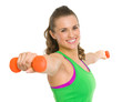 Smiling fitness young woman making exercise with dumbbells