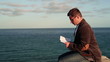 Video: Young handsome man reading book by the sea Young handsome man reading book by the sea