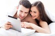 Photo: Couple using digital tablet in bed Couple using digital tablet in bed
