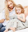 Mother and daughter wiht tablet at sofa