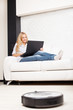Woman lying on the sofa, and the robot vacuum cleaner cleans