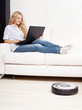 Woman lying on the sofa, and the robot vacuum cleaner cleans