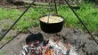Boiling soup in a vintage kettle hanging over a campfire