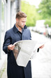 Mann im Trenchcoat und mit Zeitung