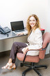 Photo: Smiling woman sitting at office desk Smiling woman sitting at office desk