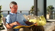 Mature man looking at picture album on the balcony