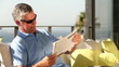 Mature man taking off his sunglasses while reading newspaper