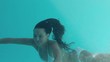 Smiling brunette swimming underwater and looking at camera