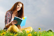 Beautiful girl lies on meadow and reads the boo