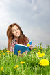 Beautiful girl lies on meadow and reads the boo