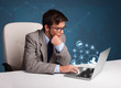 Young man sitting at desk and typing on laptop with social netwo