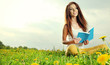 Beautiful girl lies on meadow and reads the boo