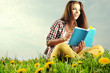 Beautiful girl lies on meadow and reads the boo