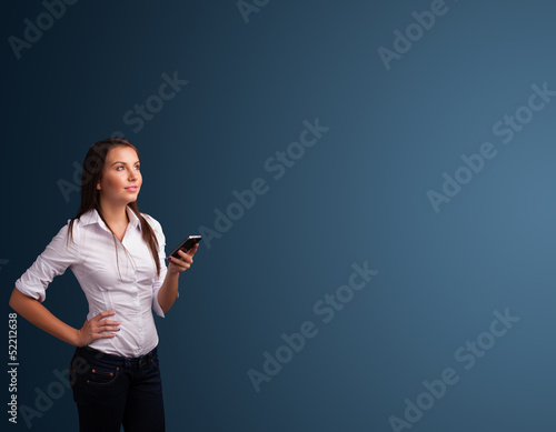 Photo: Young woman standing and typing on her phone with copy space Young woman standing and typing on her phone with copy space