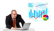 Businessman sitting at desk with laptop and statistics