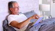 Elderly man reading book in bed