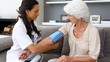 Home nurse checking her elderly patients blood pressure