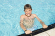 Cute boy swimming and playing in water in swimming pool