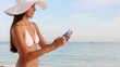 Woman with hat applying sunscreen protection