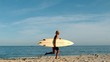 Woman running on the beach with her surfboard