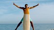 Attractive man hiding behind his surfboard