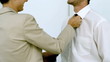 Businesswoman helping a man tying his tie