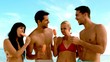 Friends laughing and eating ice cream on the beach