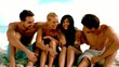 Friends laughing and chatting together on the beach