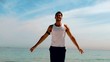 Sportsman doing jumping jacks on the beach